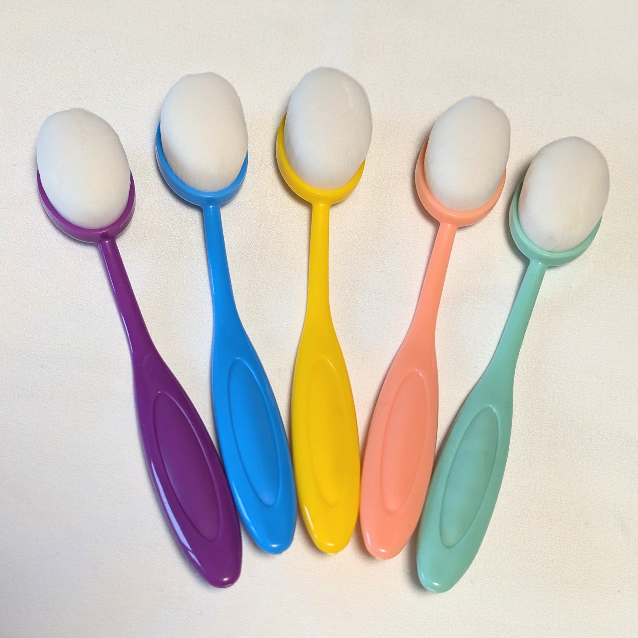 Set of five large colorful ink blending brushes with bright purple, blue, yellow, pink, and green handles arranged for card making.